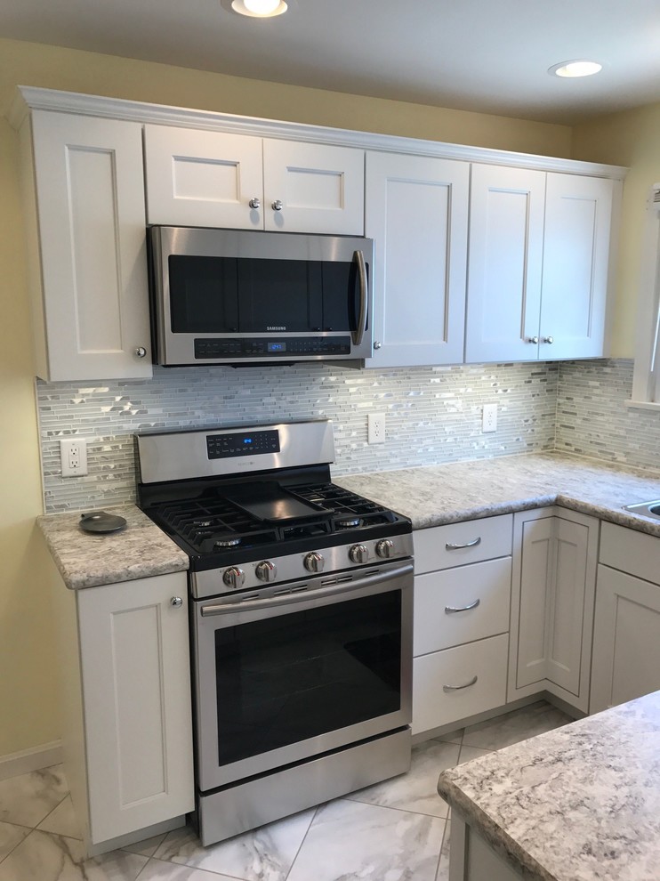 Enclosed kitchen - small transitional u-shaped limestone floor and gray floor enclosed kitchen idea with a drop-in sink, recessed-panel cabinets, white cabinets, laminate countertops, white backsplash, mosaic tile backsplash, stainless steel appliances and no island