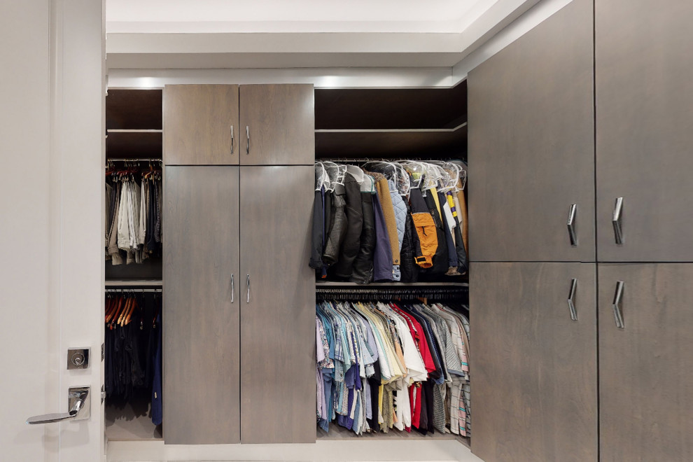 Photo of a large modern men's walk-in wardrobe in Orange County with flat-panel cabinets, grey cabinets, porcelain floors, beige floor and coffered.