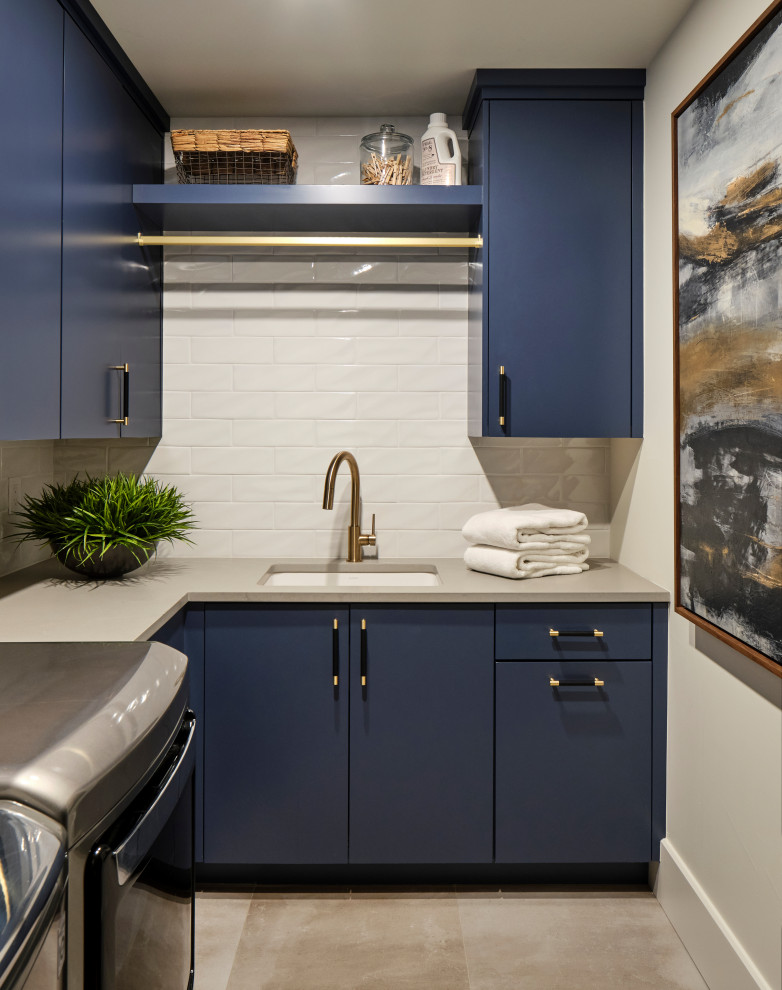 Small contemporary l-shaped dedicated laundry room in Denver with an undermount sink, flat-panel cabinets, blue cabinets, quartz benchtops, white splashback, subway tile splashback, white walls, limestone floors, a side-by-side washer and dryer, grey floor and grey benchtop.