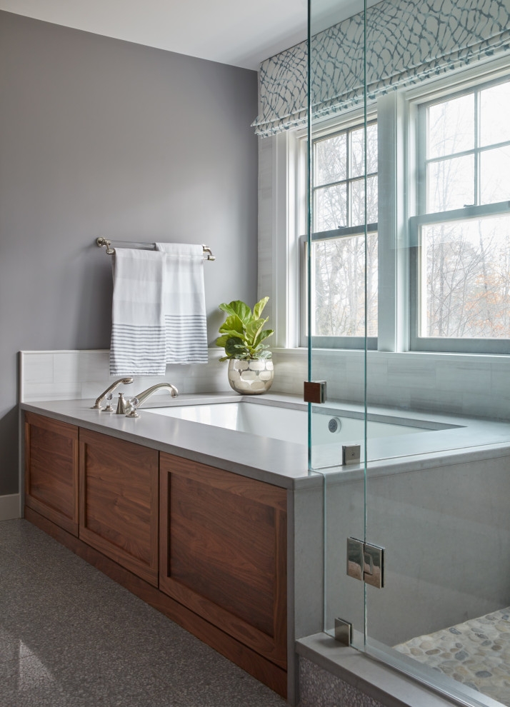 This is an example of a mid-sized transitional master bathroom in Boston with medium wood cabinets, white tile, white walls, terrazzo floors, an undermount sink, grey floor, a hinged shower door, grey benchtops, an enclosed toilet, a double vanity and a built-in vanity.