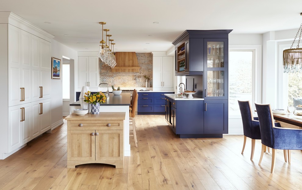 This is an example of an expansive transitional u-shaped eat-in kitchen in Toronto with an undermount sink, shaker cabinets, blue cabinets, quartz benchtops, panelled appliances, light hardwood floors, with island, brown floor and blue benchtop.