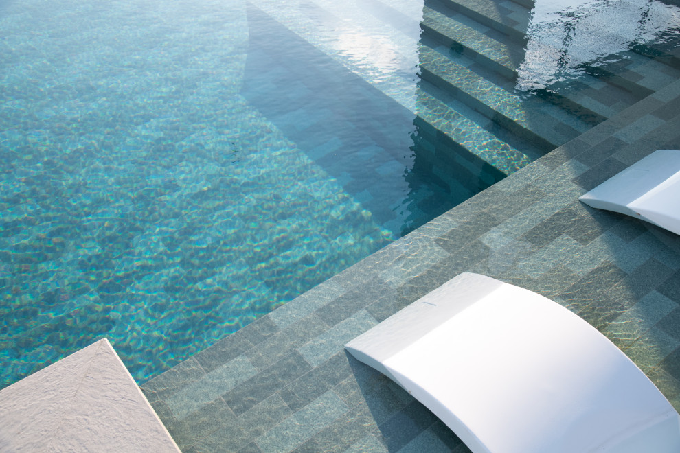 Esempio di una piscina tropicale personalizzata di medie dimensioni e dietro casa con paesaggistica bordo piscina e piastrelle