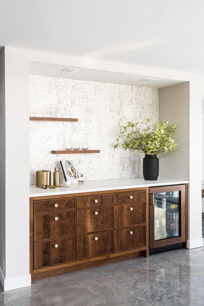 Inspiration for a transitional single-wall home bar in Minneapolis with no sink, medium wood cabinets, beige splashback, concrete floors, grey floor and white benchtop.