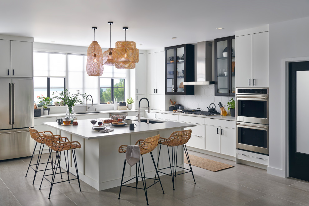 Transitional l-shaped gray floor eat-in kitchen photo with a drop-in sink, shaker cabinets, white cabinets, white backsplash, stainless steel appliances, an island and gray countertops
