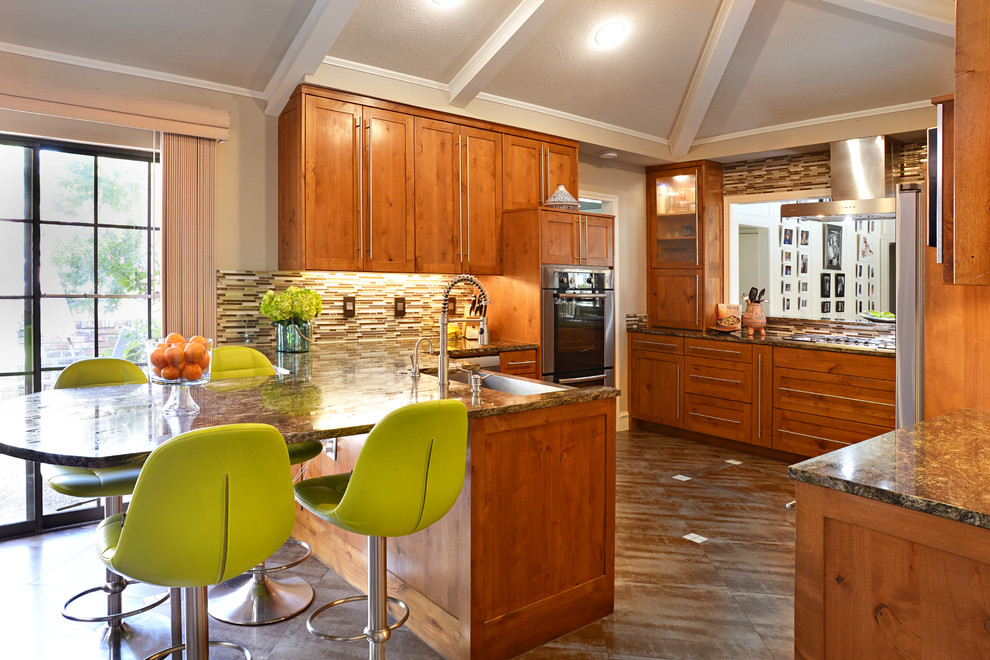 Example of a large transitional u-shaped travertine floor eat-in kitchen design in Dallas with a farmhouse sink, medium tone wood cabinets, granite countertops, multicolored backsplash, matchstick tile backsplash, stainless steel appliances and a peninsula