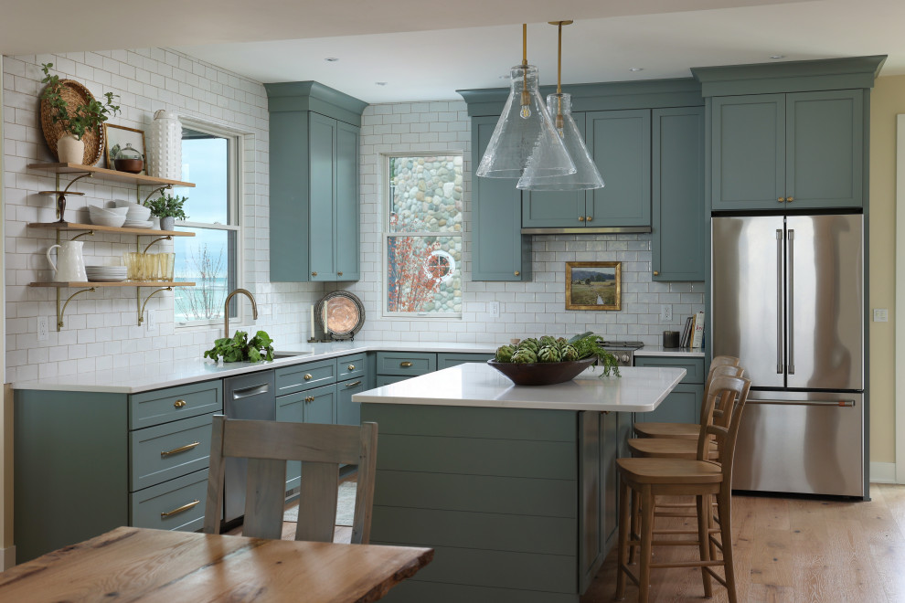 Inspiration for a beach style l-shaped kitchen in Grand Rapids with an undermount sink, shaker cabinets, turquoise cabinets, white splashback, subway tile splashback, stainless steel appliances, medium hardwood floors, with island, brown floor and white benchtop.