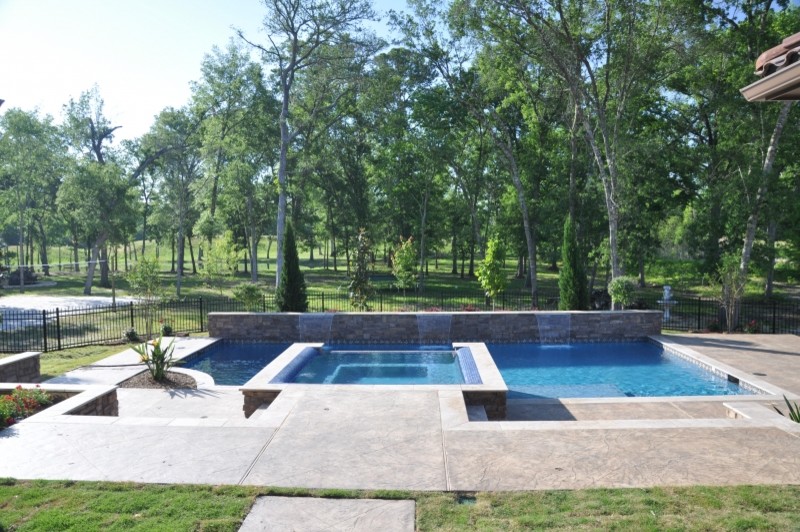 Large transitional backyard stamped concrete and custom-shaped hot tub photo in Houston