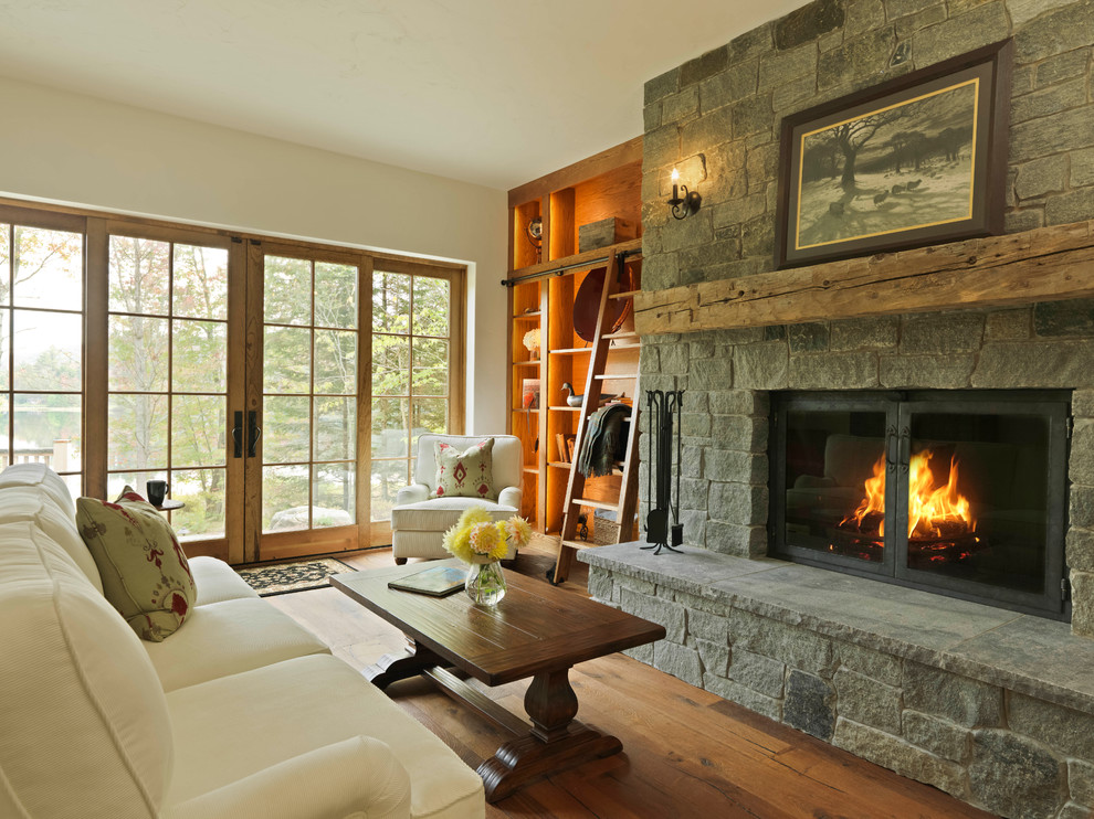 Photo of a country living room in Burlington with white walls, medium hardwood floors, a standard fireplace and a stone fireplace surround.