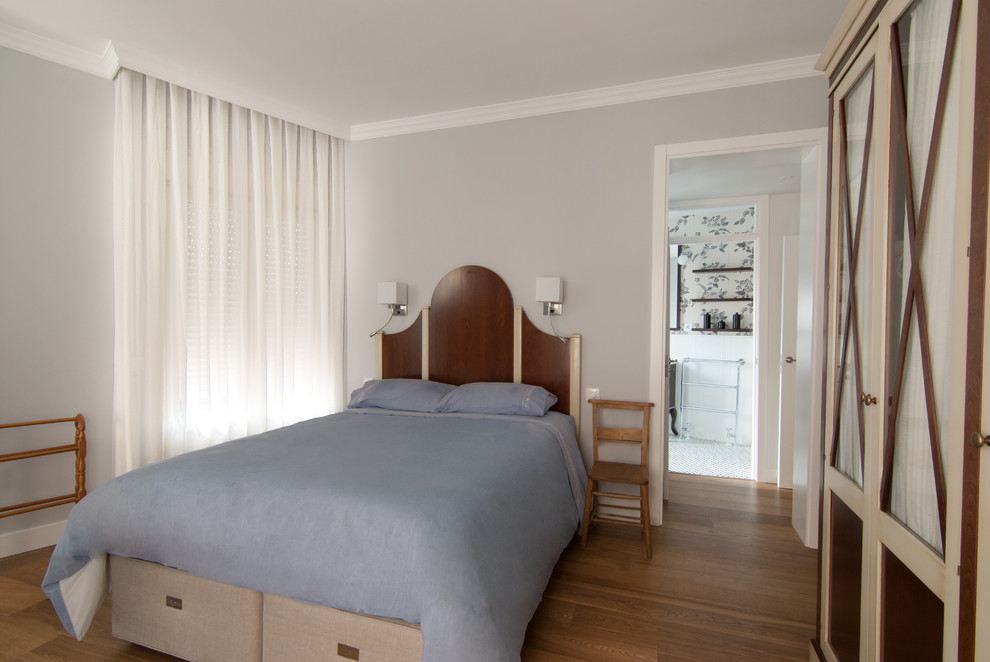 Photo of a mid-sized transitional master bedroom in Madrid with grey walls and medium hardwood floors.