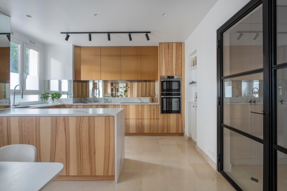 This is an example of a contemporary u-shaped kitchen in Paris with an undermount sink, flat-panel cabinets, medium wood cabinets, stainless steel appliances, a peninsula, beige floor and white benchtop.