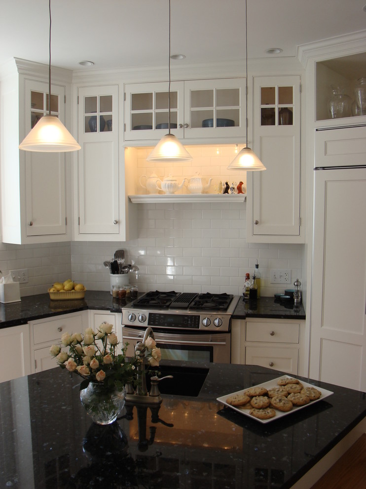 Small traditional u-shaped eat-in kitchen in Portland Maine with an undermount sink, beaded inset cabinets, white cabinets, white splashback, subway tile splashback, stainless steel appliances, medium hardwood floors, with island and recycled glass benchtops.