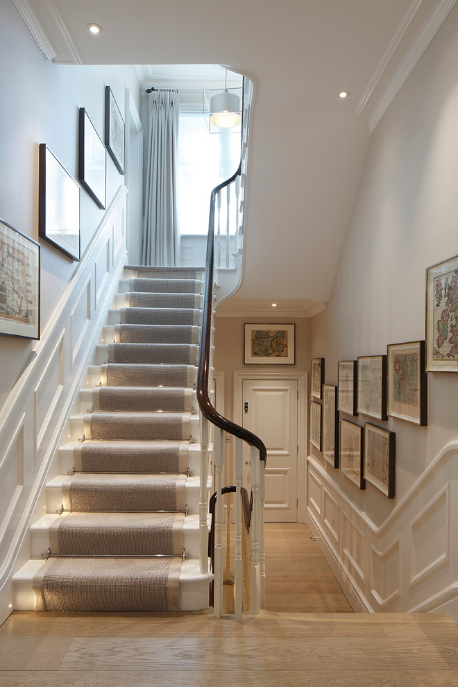 Traditional painted wood u-shaped staircase in London with painted wood risers and wood railing.