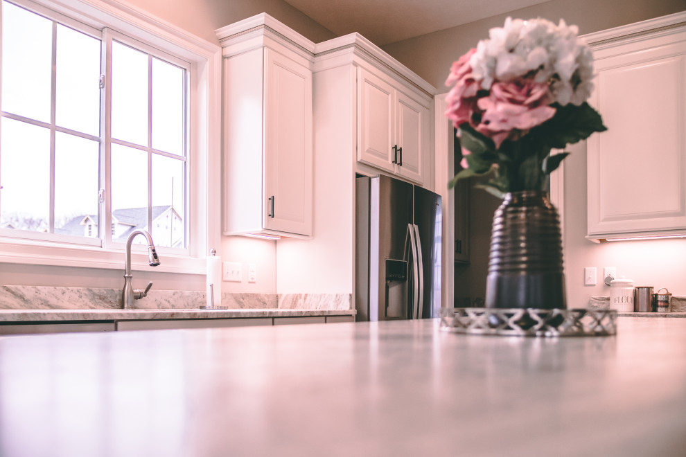Large transitional galley light wood floor and beige floor eat-in kitchen photo with an undermount sink, raised-panel cabinets, white cabinets, granite countertops, stainless steel appliances, an island and white countertops