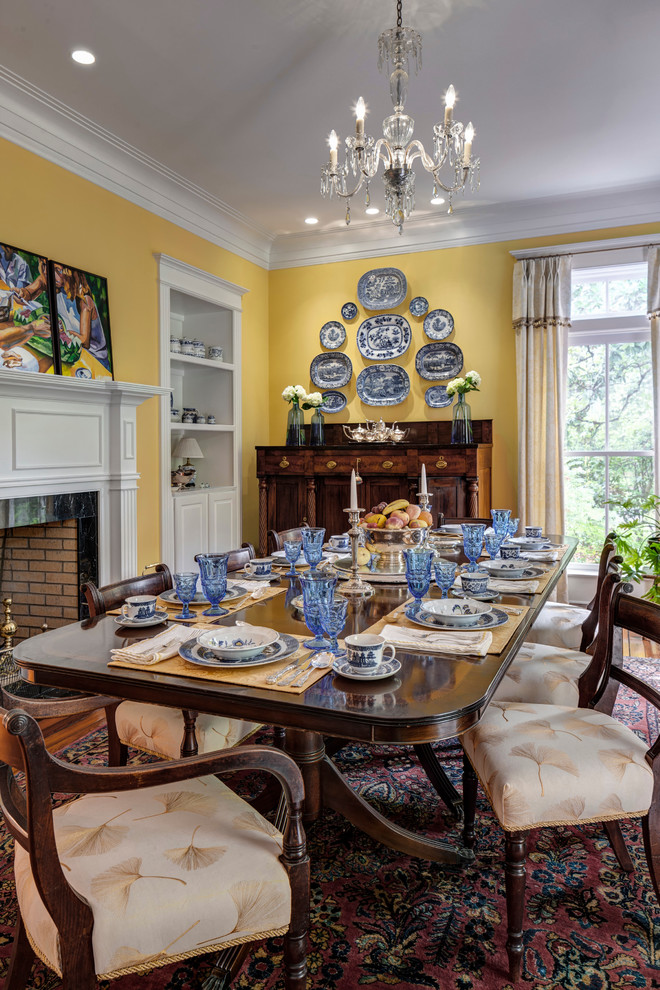 Photo of a traditional dining room in Atlanta with yellow walls, dark hardwood floors and a standard fireplace.