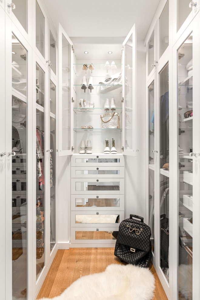 Inspiration for a transitional women's walk-in wardrobe in New York with shaker cabinets, white cabinets, medium hardwood floors and brown floor.