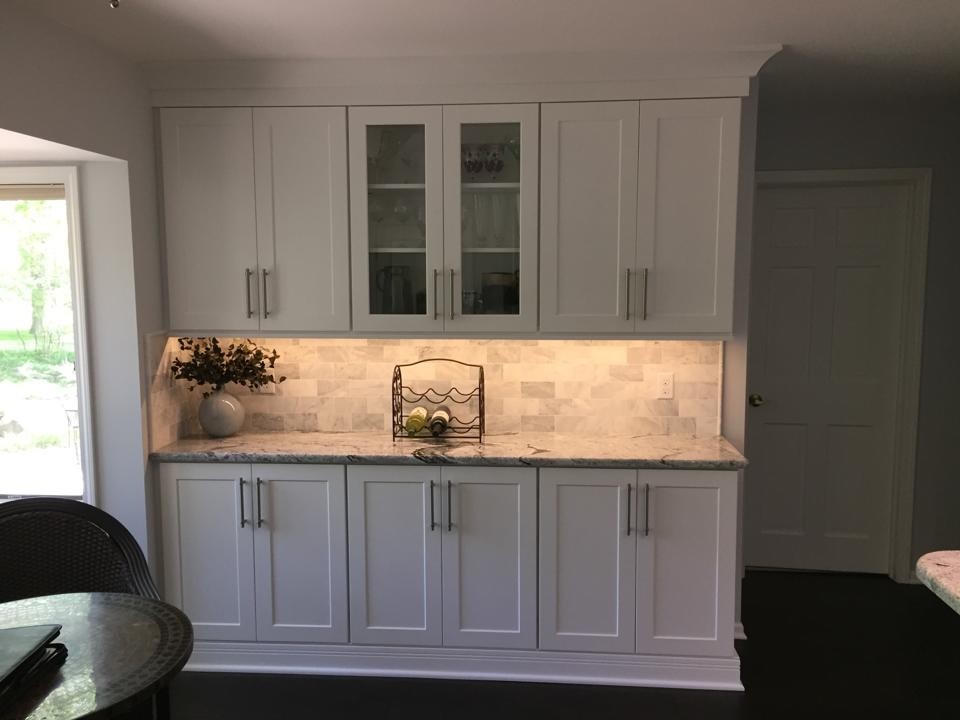 Example of a mid-sized transitional u-shaped dark wood floor eat-in kitchen design in Detroit with an undermount sink, shaker cabinets, white cabinets, granite countertops, white backsplash, stone tile backsplash, stainless steel appliances and a peninsula