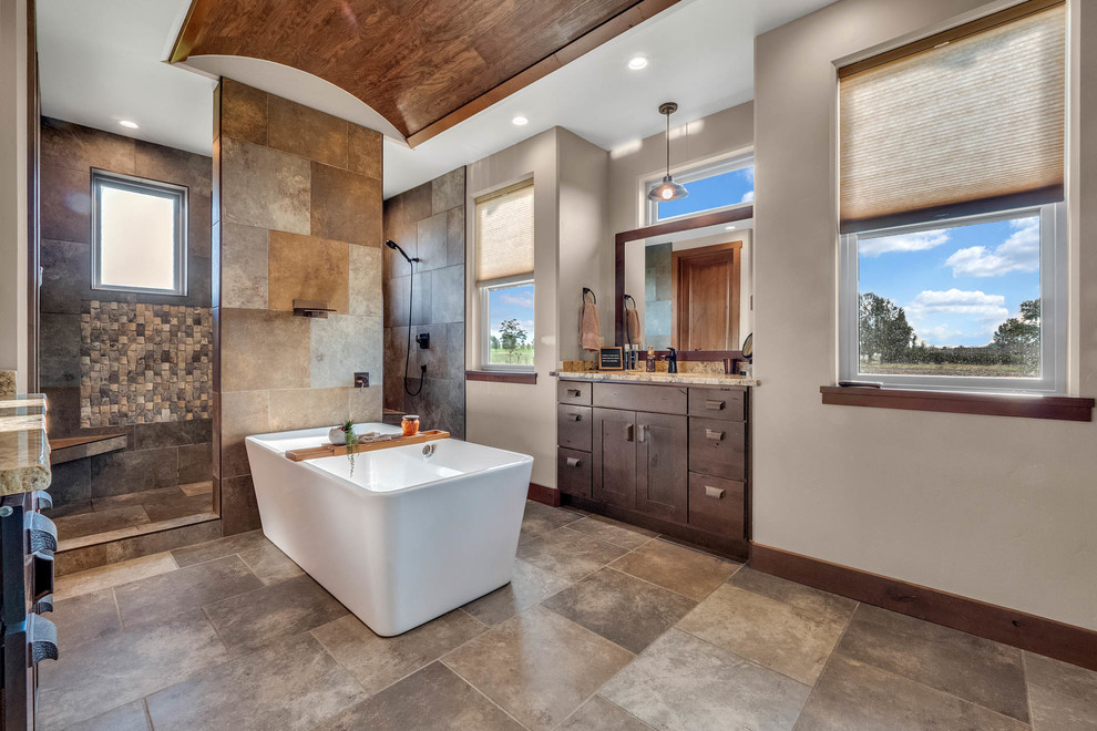 Design ideas for a mid-sized country bathroom in Denver with dark wood cabinets, a freestanding tub, a double shower, travertine, travertine floors, an undermount sink, granite benchtops, shaker cabinets, brown tile, grey walls, brown floor and brown benchtops.