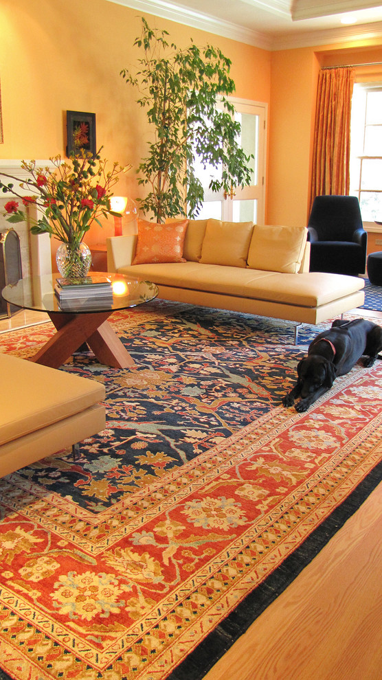 Esempio di un soggiorno design con pareti arancioni e camino classico