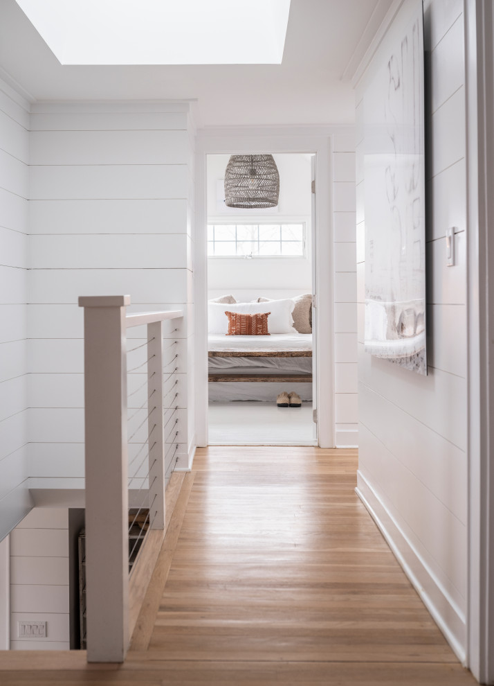 Inspiration for a large beach style hallway in Other with white walls, light hardwood floors, brown floor and planked wall panelling.