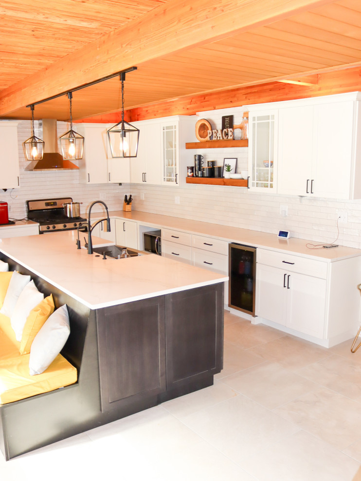 Large arts and crafts l-shaped eat-in kitchen in Chicago with a farmhouse sink, shaker cabinets, white cabinets, quartzite benchtops, white splashback, glass sheet splashback, stainless steel appliances, porcelain floors, with island, grey floor, white benchtop and exposed beam.