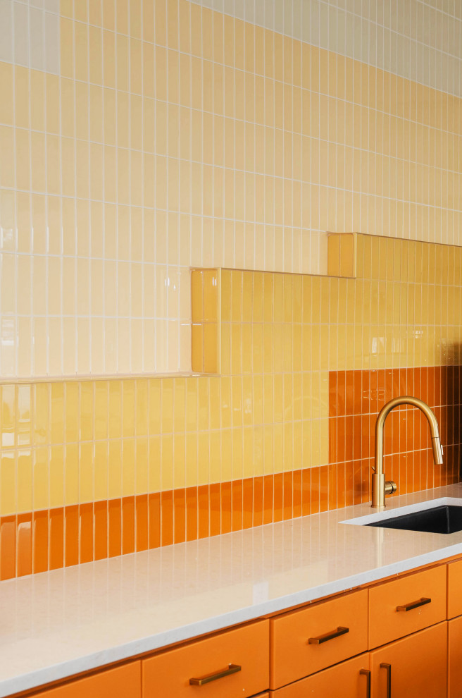 Inspiration pour une grande cuisine ouverte linéaire minimaliste avec un évier posé, des portes de placard oranges, une crédence jaune, une crédence en carreau de verre et un électroménager en acier inoxydable.