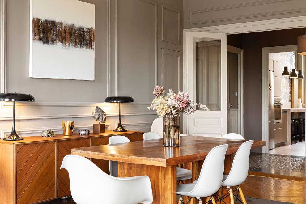 Transitional open plan dining in Lyon with grey walls, medium hardwood floors, no fireplace, brown floor and panelled walls.