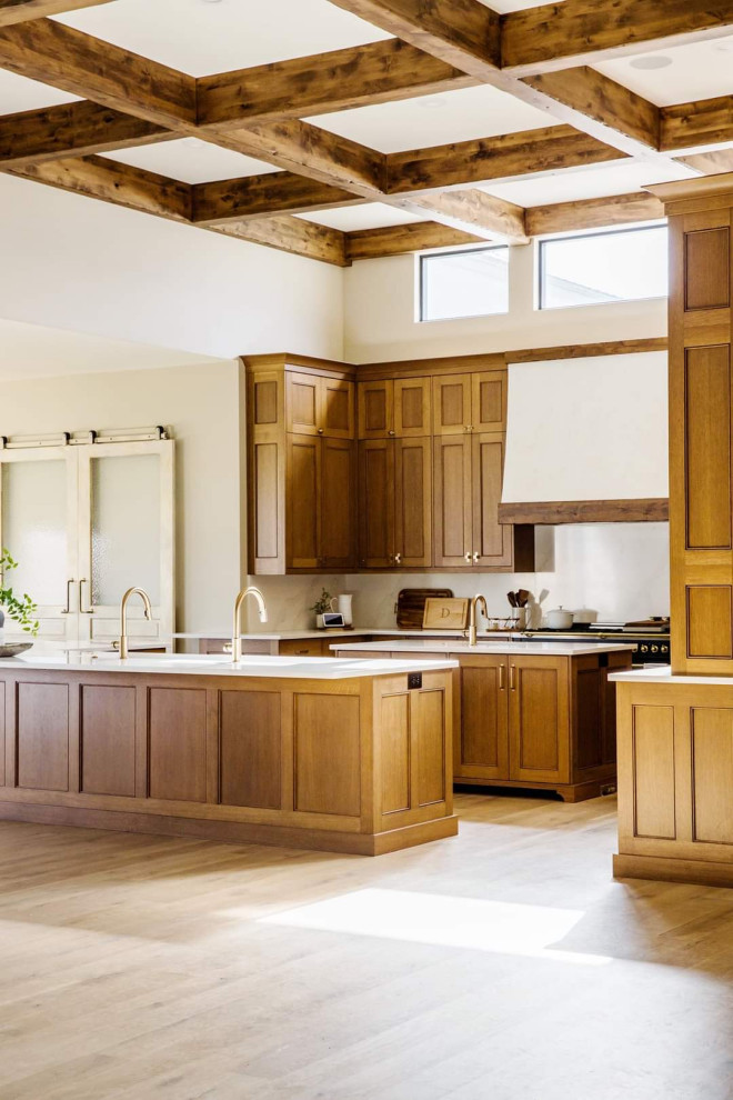 他の地域にある高級な広いトラディショナルスタイルのおしゃれなキッチン (アンダーカウンターシンク、インセット扉のキャビネット、中間色木目調キャビネット、クオーツストーンカウンター、白いキッチンパネル、クオーツストーンのキッチンパネル、黒い調理設備、無垢フローリング、茶色い床、白いキッチンカウンター、表し梁) の写真