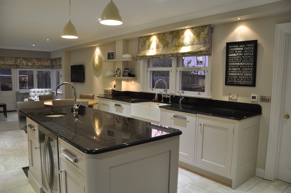 Design ideas for a mid-sized traditional galley eat-in kitchen in Hertfordshire with recessed-panel cabinets, beige cabinets, granite benchtops, with island, an undermount sink, stainless steel appliances and ceramic floors.