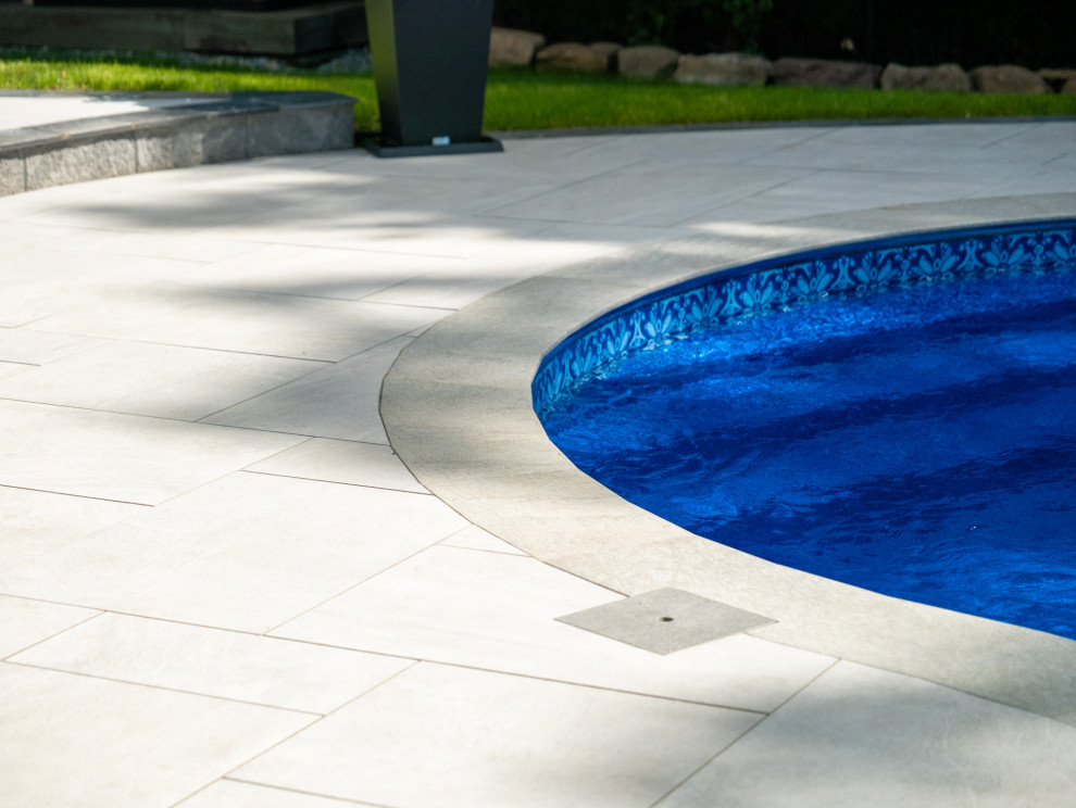 Inspiration for a large contemporary back custom shaped natural swimming pool in New York with with pool landscaping and tiled flooring.
