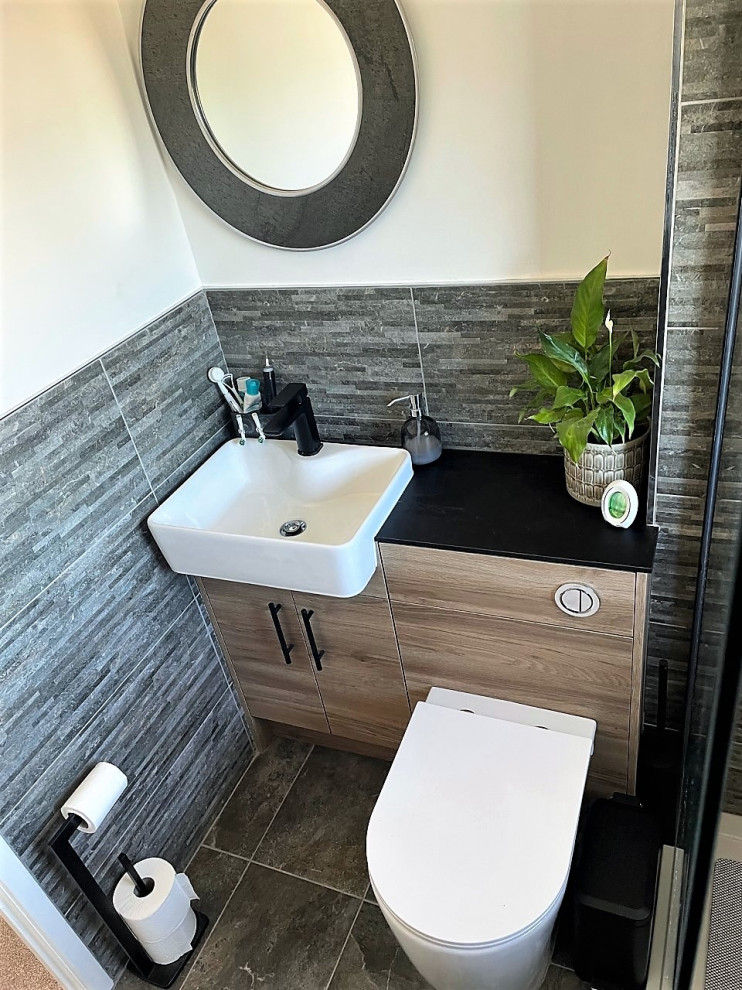 Design ideas for a mid-sized modern kids bathroom in Other with flat-panel cabinets, medium wood cabinets, an open shower, a one-piece toilet, gray tile, porcelain tile, a drop-in sink, laminate benchtops, an open shower, black benchtops, a single vanity and a built-in vanity.
