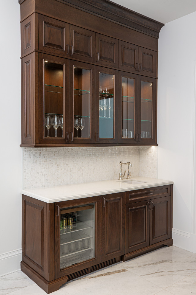 Mid-sized traditional single-wall wet bar in Miami with an undermount sink, raised-panel cabinets, dark wood cabinets, quartz benchtops, grey splashback, mirror splashback, marble floors, grey floor and white benchtop.