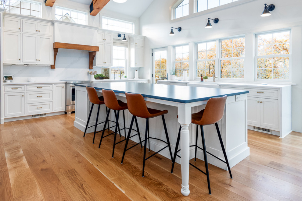 Kitchen - large traditional light wood floor, brown floor and vaulted ceiling kitchen idea in Philadelphia with a farmhouse sink, recessed-panel cabinets, medium tone wood cabinets, quartz countertops, white backsplash, quartz backsplash, paneled appliances, two islands and black countertops