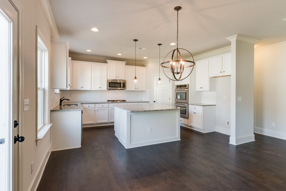 Eat-in kitchen - large transitional u-shaped dark wood floor and brown floor eat-in kitchen idea with an undermount sink, recessed-panel cabinets, white cabinets, granite countertops, white backsplash, subway tile backsplash, stainless steel appliances and an island