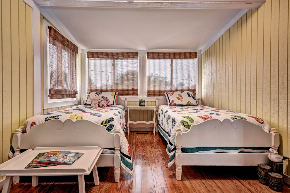This is an example of a small beach style gender-neutral kids' bedroom for kids 4-10 years old in Other with beige walls, medium hardwood floors and brown floor.