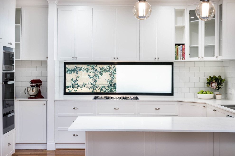 This is an example of a contemporary kitchen in Perth with marble benchtops, white splashback, subway tile splashback and light hardwood floors.