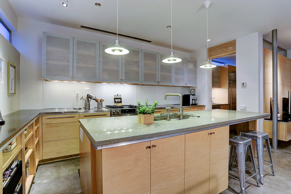 Mid-sized modern galley eat-in kitchen in Portland with an undermount sink, flat-panel cabinets, light wood cabinets, recycled glass benchtops, white splashback, glass sheet splashback, stainless steel appliances, concrete floors and with island.