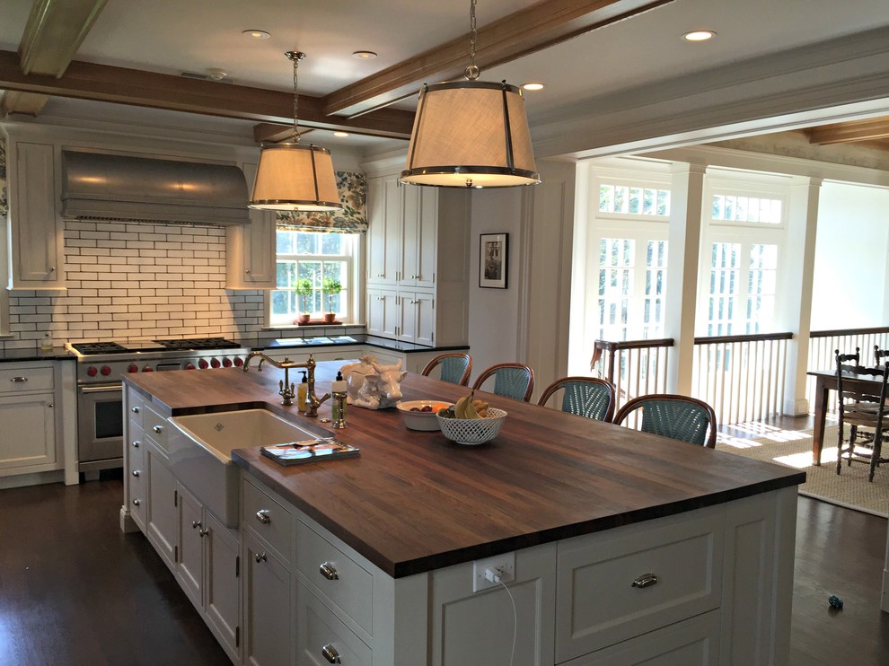 Inspiration for a large transitional u-shaped eat-in kitchen in Cincinnati with a farmhouse sink, shaker cabinets, white cabinets, wood benchtops, white splashback, subway tile splashback, stainless steel appliances, dark hardwood floors and with island.