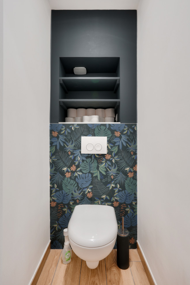 This is an example of a small contemporary cloakroom in Paris with blue cabinets, a wall mounted toilet, blue tiles, ceramic tiles, blue walls, ceramic flooring, beige floors, a built in vanity unit and wallpapered walls.