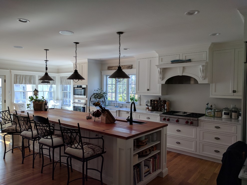 Inspiration for a large transitional l-shaped medium tone wood floor and brown floor open concept kitchen remodel in Boston with a farmhouse sink, shaker cabinets, white cabinets, stainless steel appliances and an island