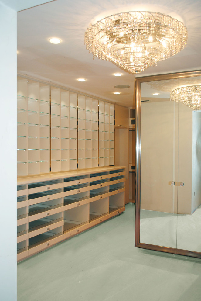 Large modern women's dressing room in Miami with glass-front cabinets and white cabinets.