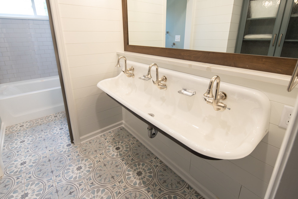 Mid-sized transitional bathroom in Indianapolis with blue cabinets, an alcove tub, a shower/bathtub combo, a two-piece toilet, subway tile, white walls, ceramic floors, a trough sink, engineered quartz benchtops, multi-coloured floor, a shower curtain and white benchtops.