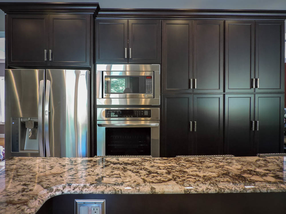 Large transitional u-shaped porcelain tile and beige floor eat-in kitchen photo in Bridgeport with an undermount sink, raised-panel cabinets, dark wood cabinets, granite countertops, green backsplash, glass tile backsplash, stainless steel appliances, an island and brown countertops