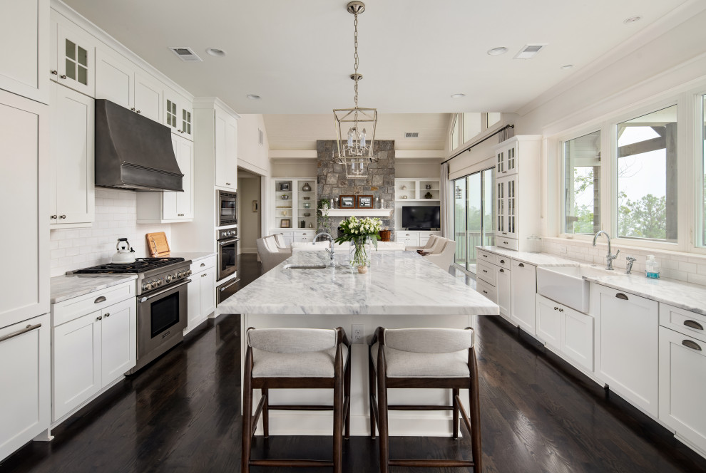 Design ideas for a mid-sized traditional galley eat-in kitchen in Atlanta with a farmhouse sink, shaker cabinets, white cabinets, quartzite benchtops, white splashback, subway tile splashback, stainless steel appliances, dark hardwood floors, with island, brown floor and white benchtop.