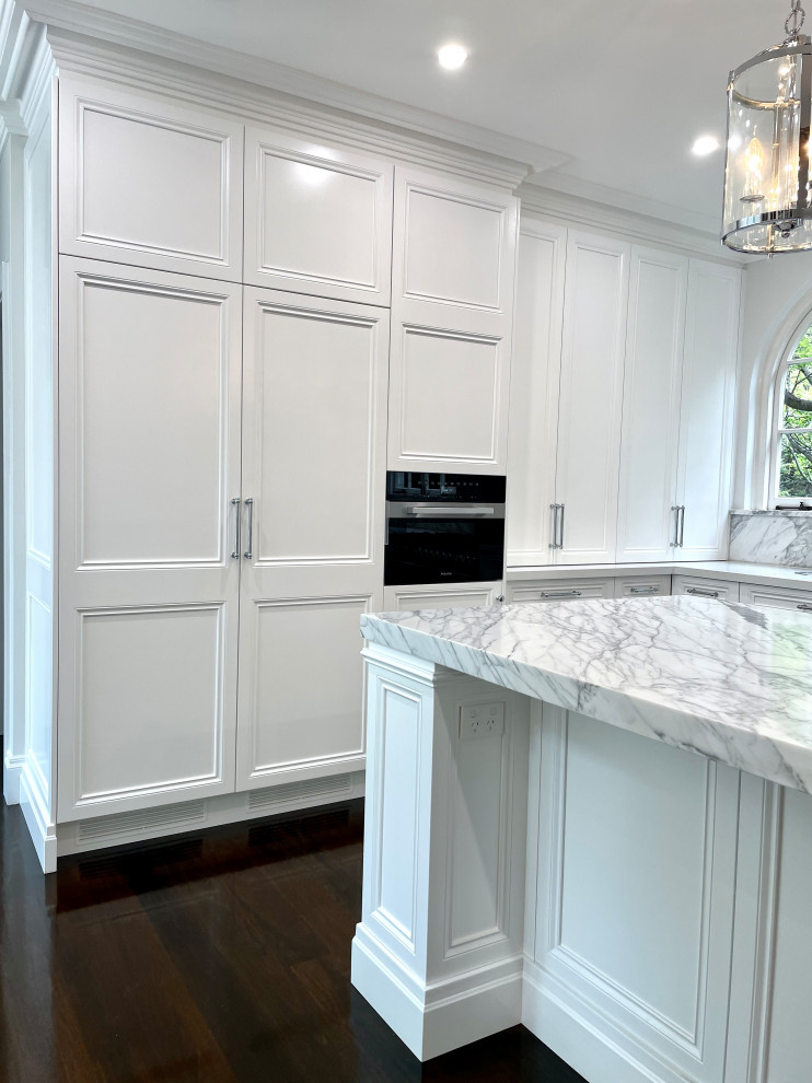 Photo of an expansive traditional u-shaped kitchen pantry in Sydney with a farmhouse sink, recessed-panel cabinets, white cabinets, marble benchtops, grey splashback, marble splashback, stainless steel appliances, dark hardwood floors, with island, brown floor, grey benchtop and recessed.