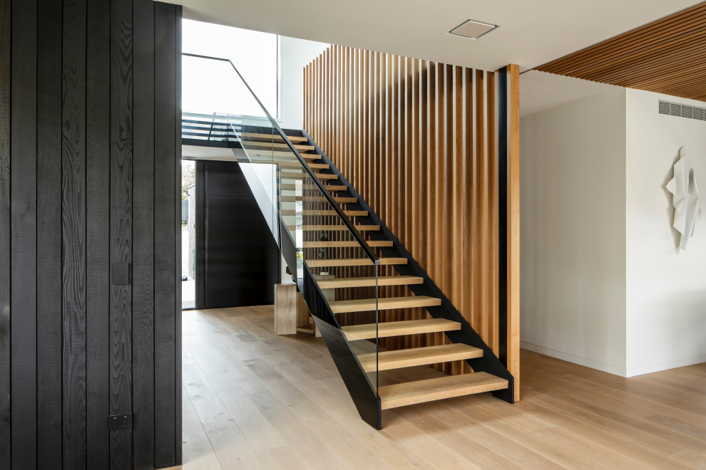 Идея дизайна: лестница на больцах в современном стиле с деревянными ступенями, стеклянными перилами и деревянными стенами без подступенок