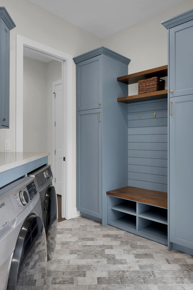 Inspiration for a large beach style l-shaped dedicated laundry room in Jacksonville with an undermount sink, shaker cabinets, blue cabinets, quartz benchtops, white splashback, subway tile splashback, white walls, brick floors, a side-by-side washer and dryer, grey floor and grey benchtop.