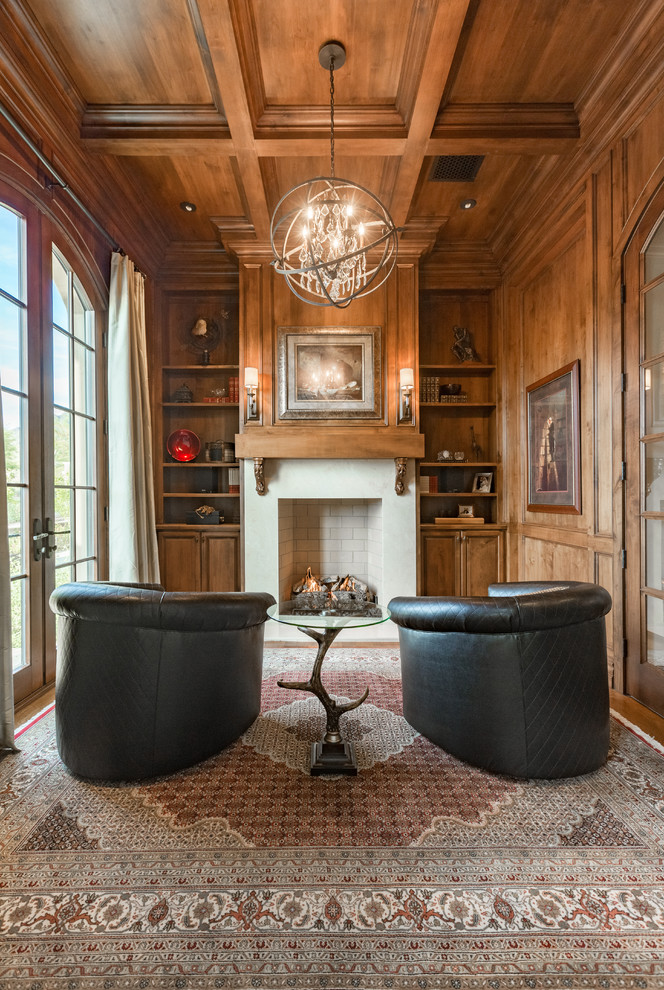 Mid-sized traditional study room in Phoenix with a standard fireplace, brown walls, medium hardwood floors, a concrete fireplace surround, a freestanding desk and brown floor.