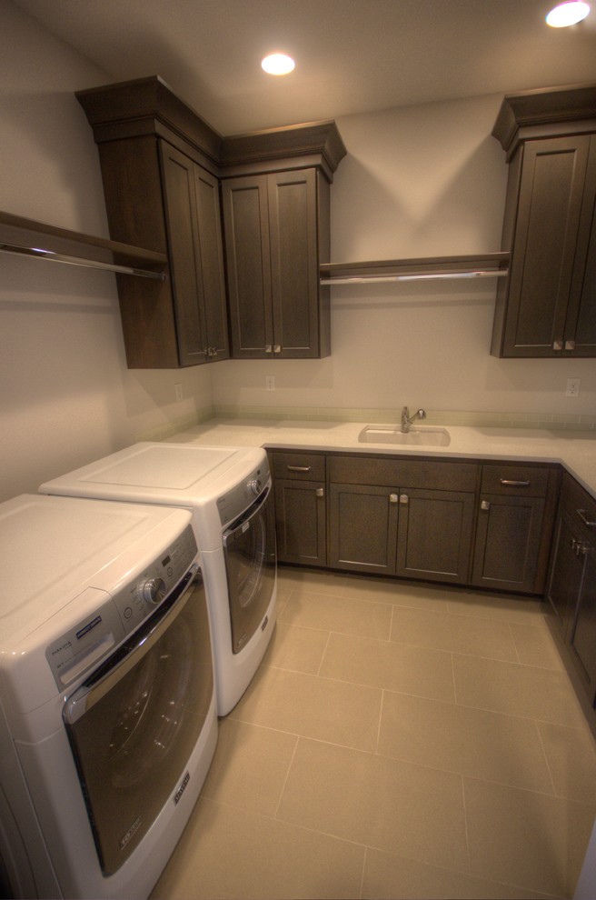 This is an example of a large transitional u-shaped laundry room in Portland with an undermount sink, shaker cabinets, grey cabinets, quartz benchtops, grey walls, porcelain floors and a side-by-side washer and dryer.