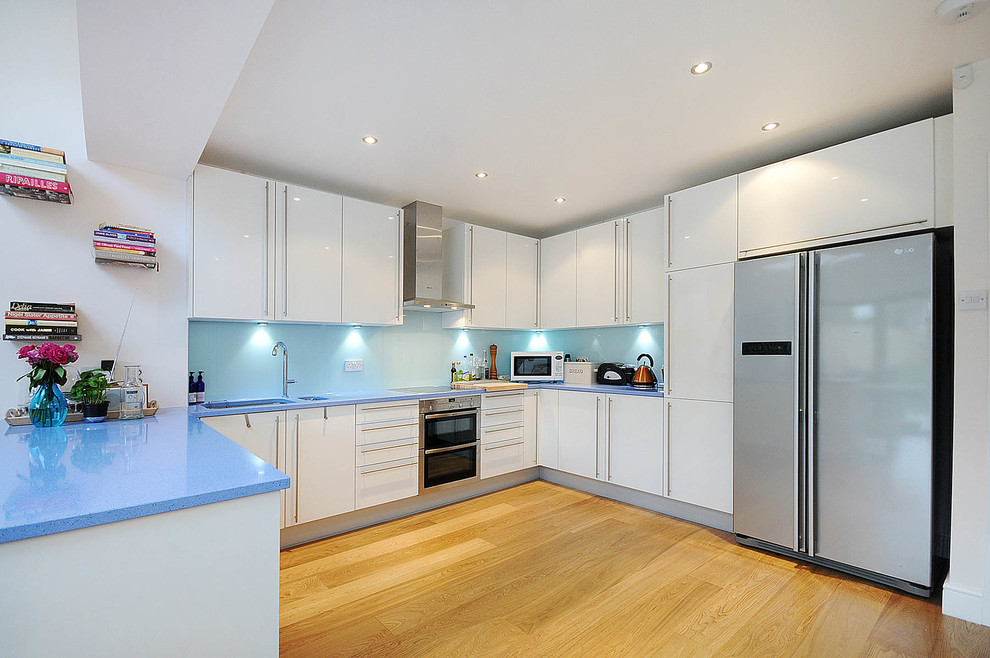 Inspiration for a large modern single-wall eat-in kitchen in London with a single-bowl sink, open cabinets, blue cabinets, quartzite benchtops, blue splashback, glass tile splashback, coloured appliances, slate floors and with island.