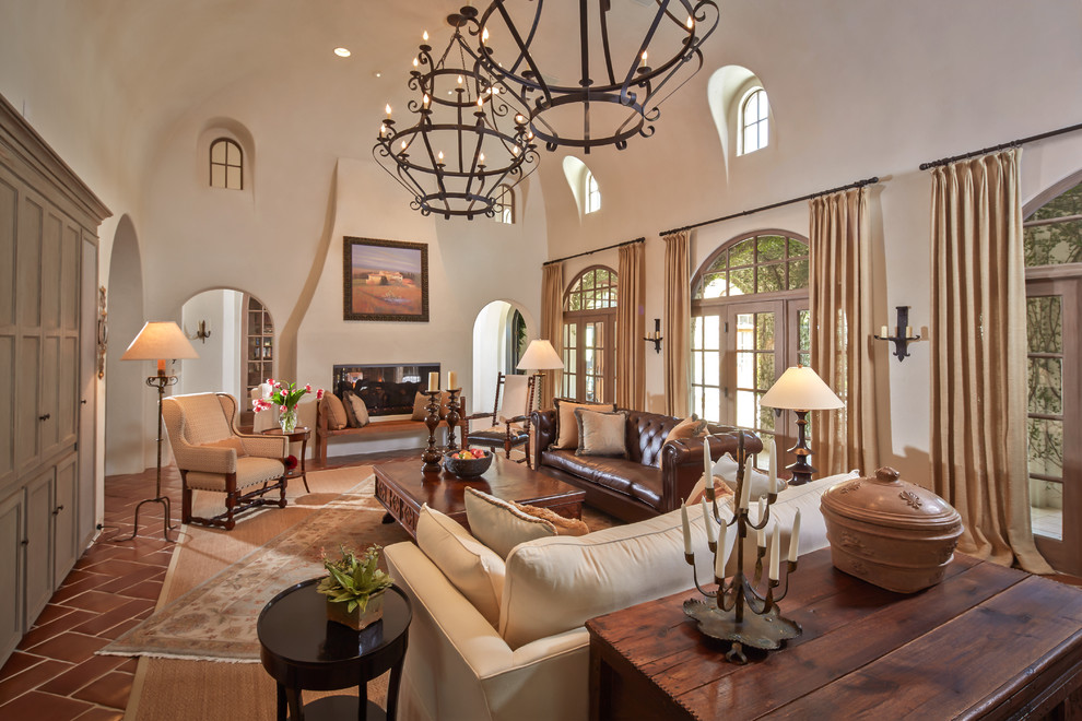 Mid-sized mediterranean formal enclosed living room in Houston with a two-sided fireplace, terra-cotta floors, beige walls, a plaster fireplace surround, no tv and red floor.